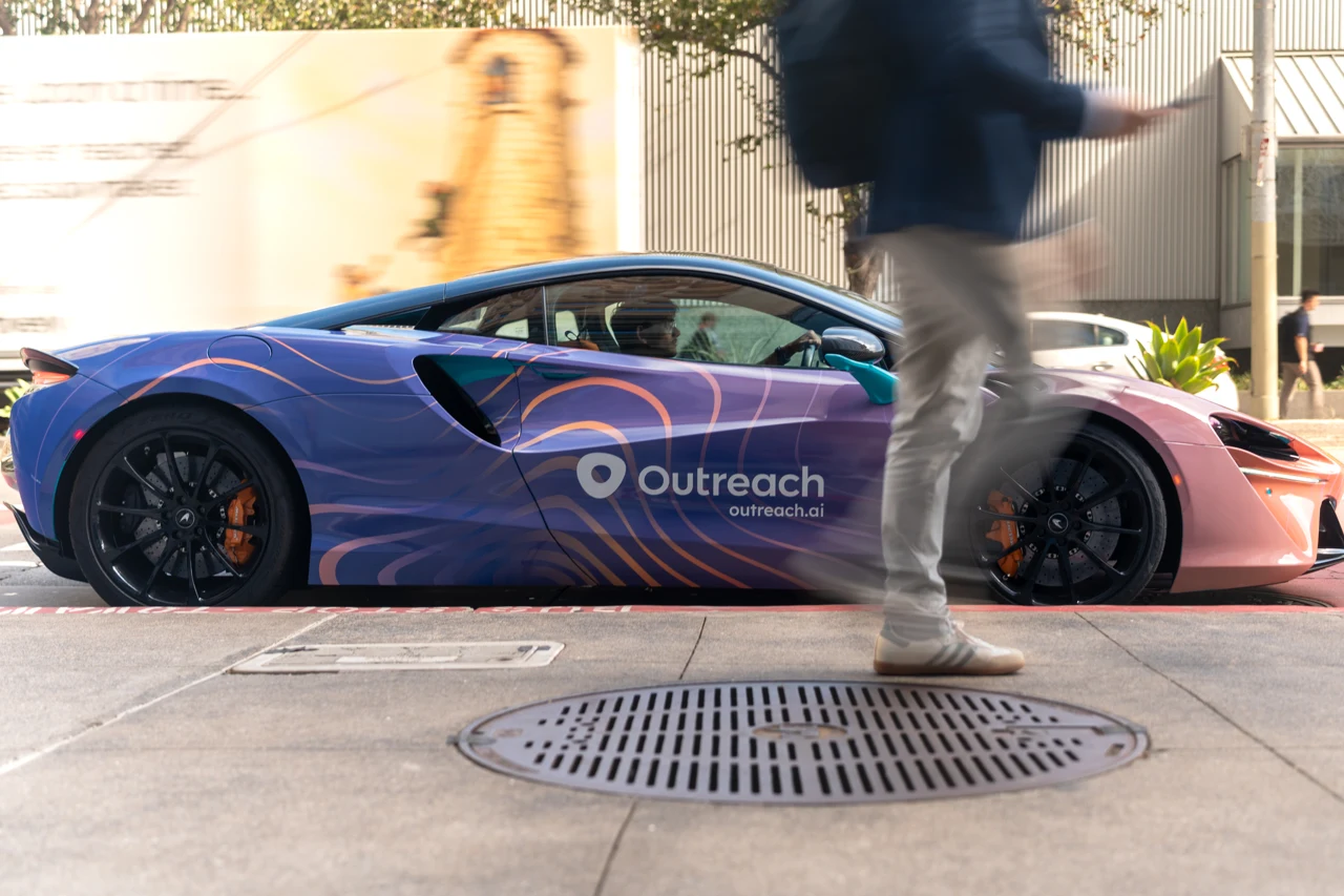 Outreach McLaren beside passing pedestrians