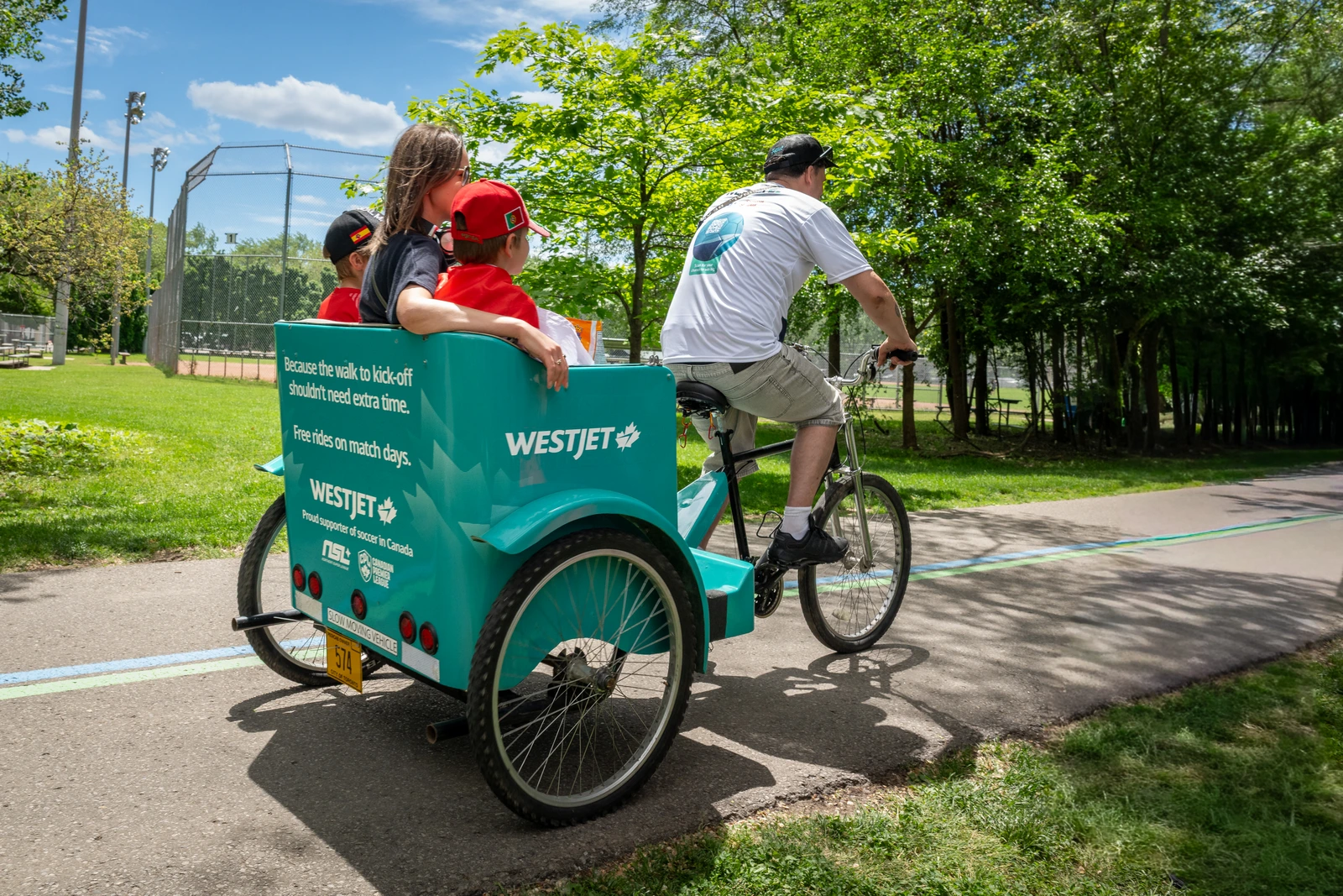WestJet branded pedicab carrying passengers along a path